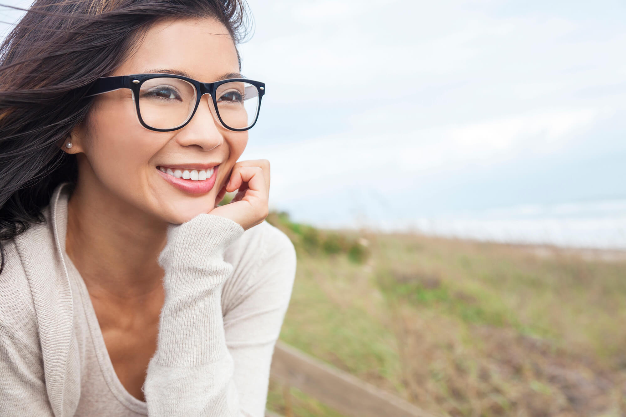 Adult with glasses smiling outdoors.