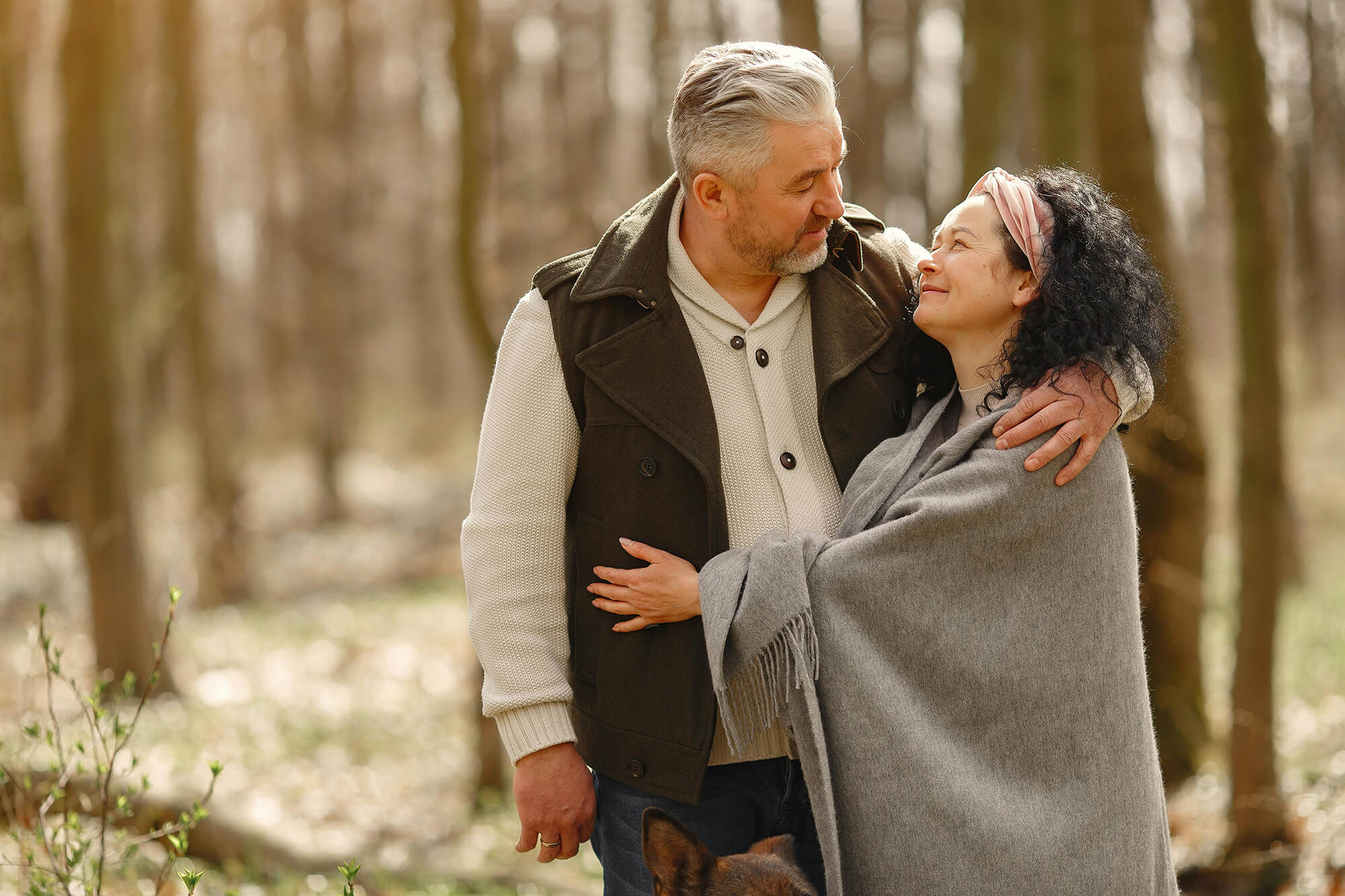 Two adults embracing each other outdoors.