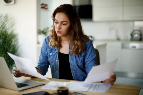 An adult looking at papers while at a desk.