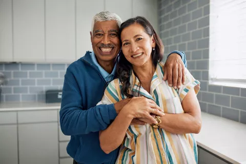 Two adults embracing each other while smiling.