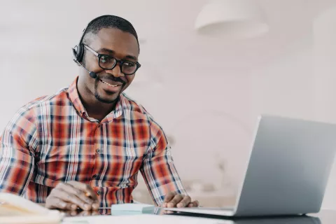 An adult with a headset using the laptop.