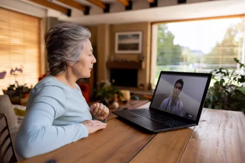 A senior person on a video call with a doctor in their living room.