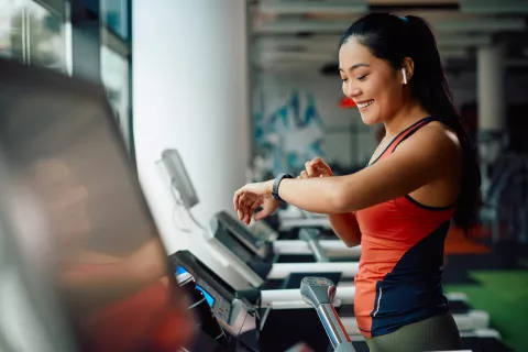 Adult checking their fitness watch while on a treadmill.