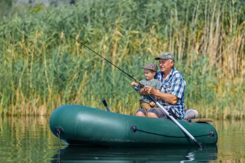 Senior adult and a child fishing on a boat.