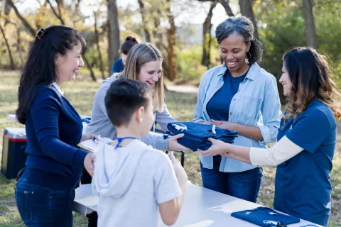 Group of adults handing out blue t-shirts.