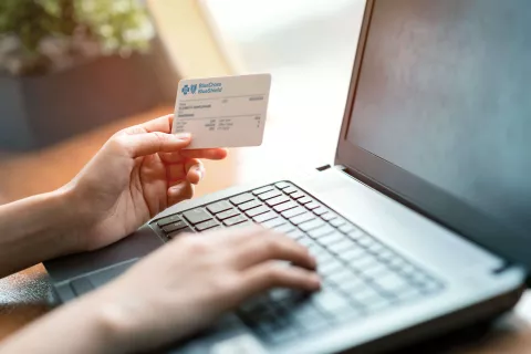 A person holding a Blue Cross Blue Shield member ID card.