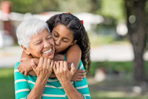 A child joyfully hugs a senior, showing love and affection.