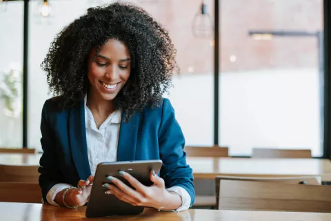 Adult using a digital tablet and smiling.