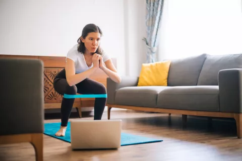 Adult exercising in the living room in front of the laptop.