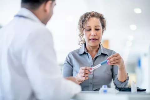 Adult filling syringe with insulin while with a doctor.