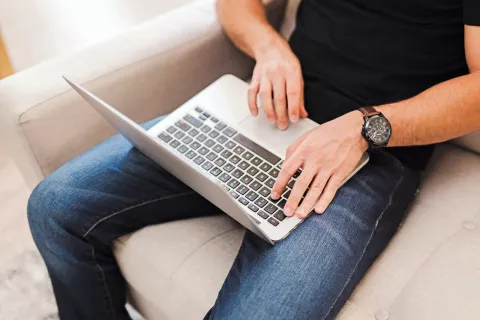 Adult sitting on the couch, using a laptop.