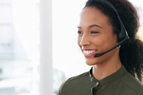 An adult with a headset on smiling.