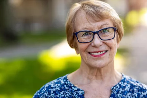 a headshot of a smiling senior wearing glasses outside