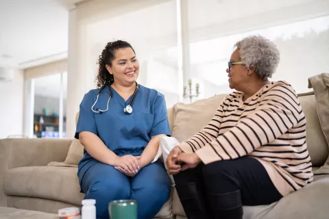 Senior and doctor talking to eachother on the couch.