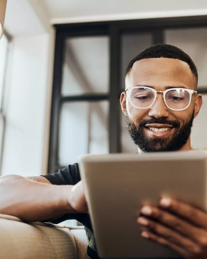 A young adult interacting with a digital tablet while on the couch.