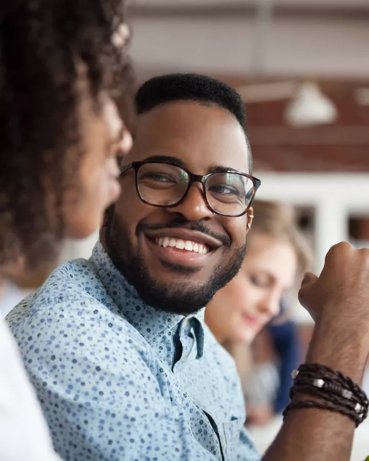 Adult smiling while at the desk with coworkers.