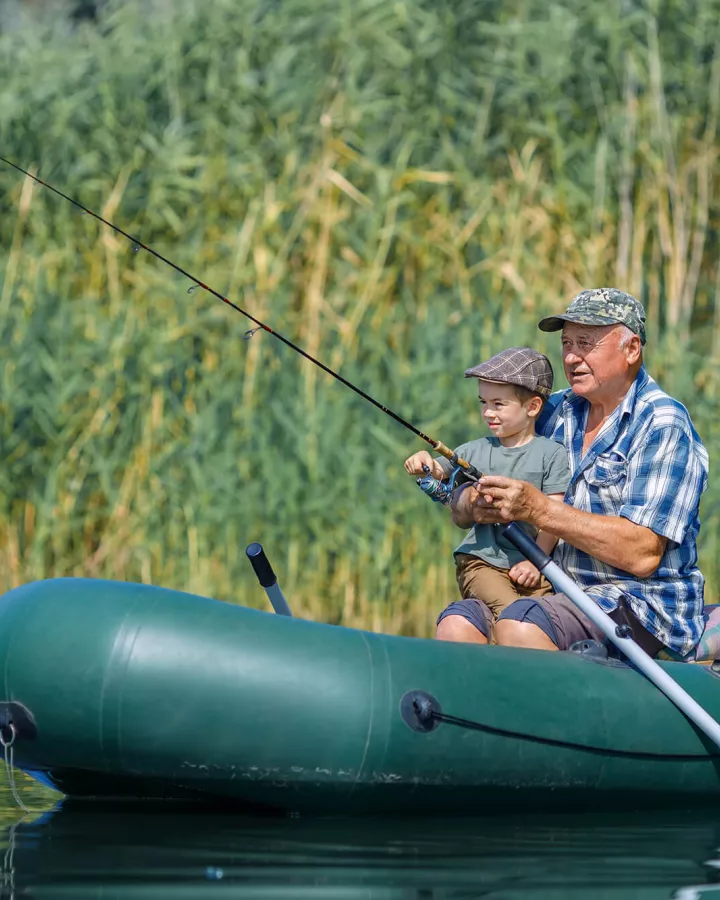 Senior adult and a child fishing on a boat.