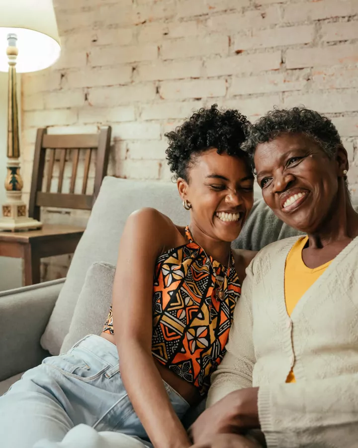 A young adult and senior adult embracing each other on the couch.