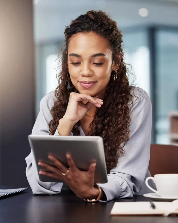 An adult looking at a digital tablet while seated at a desk.